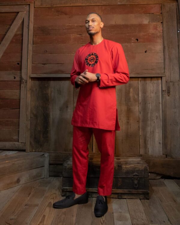 A man in red suit standing next to wooden wall.