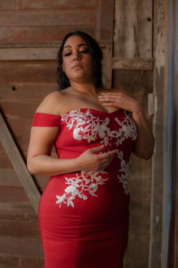 A woman in red dress touching her chest.