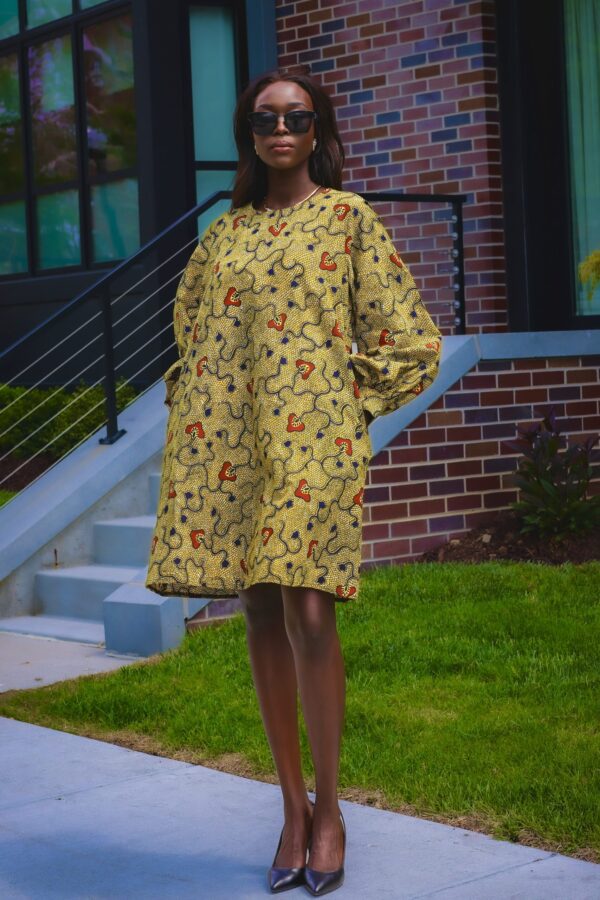 A person wearing a yellow coat standing on the grass.