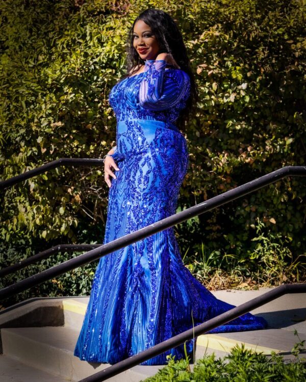 A woman in blue dress standing on steps.