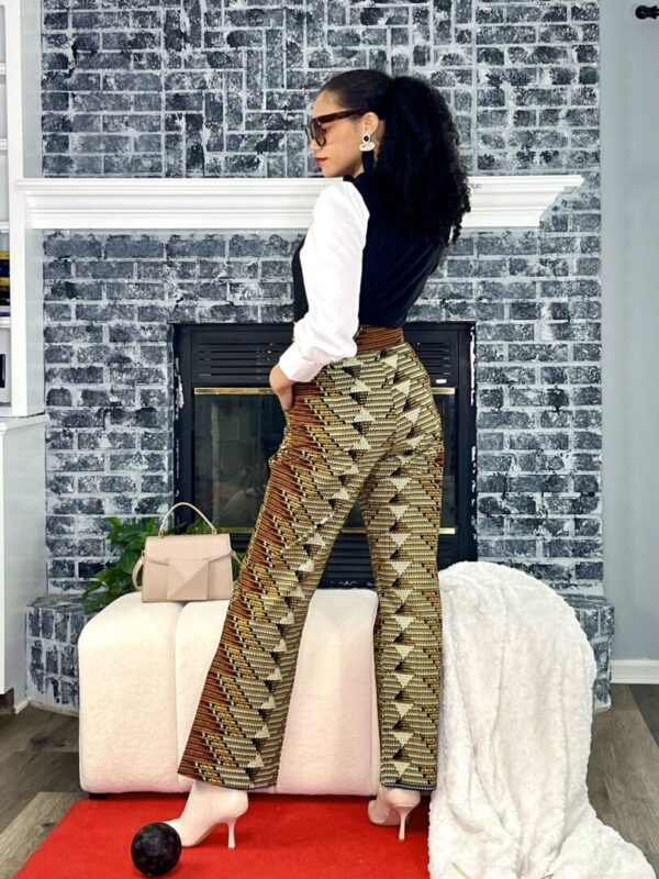 Woman in patterned pants posing by fireplace.