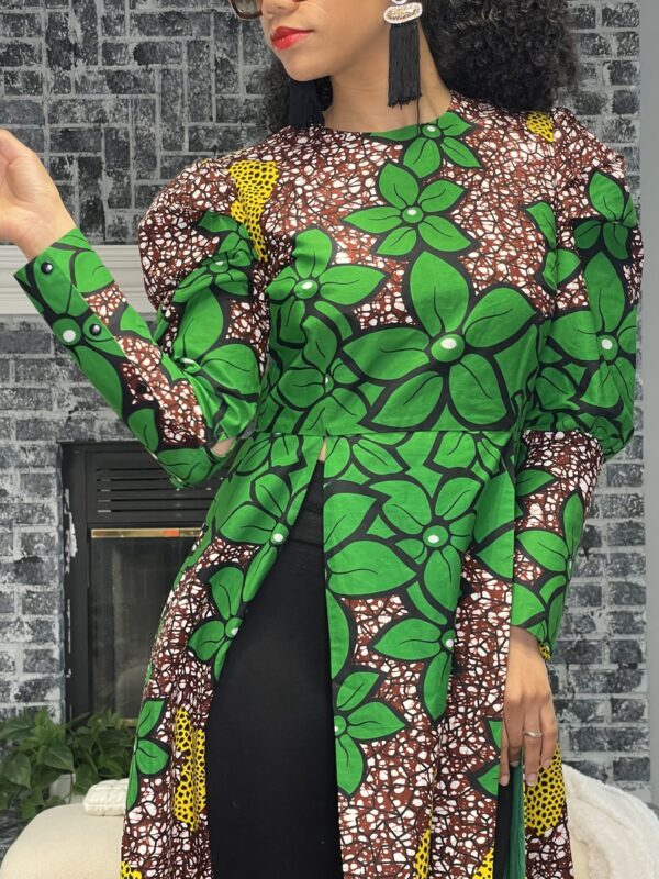 A woman in green and black outfit standing next to a brick wall.