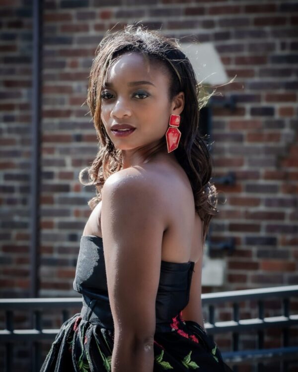 Woman in black dress with red earrings.