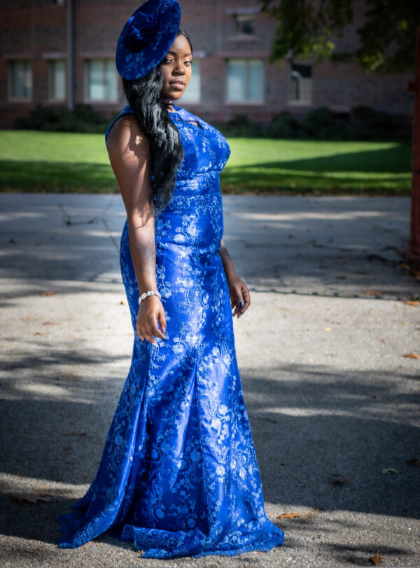 A woman in blue dress standing on the street.