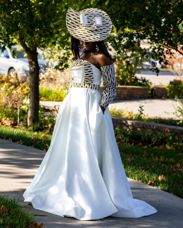 Woman in white dress and hat outdoors.
