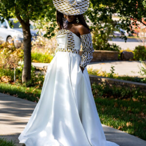 Woman in white dress and hat outdoors.