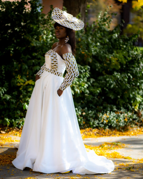 Woman in white dress and hat outdoors.