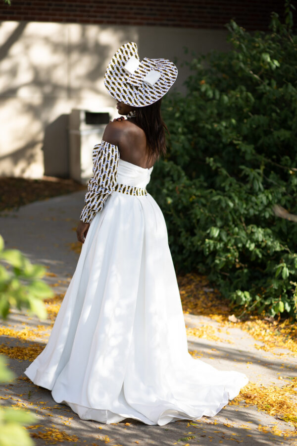 Woman in white dress and patterned hat.