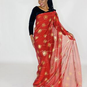 Woman wearing a red and gold patterned saree.
