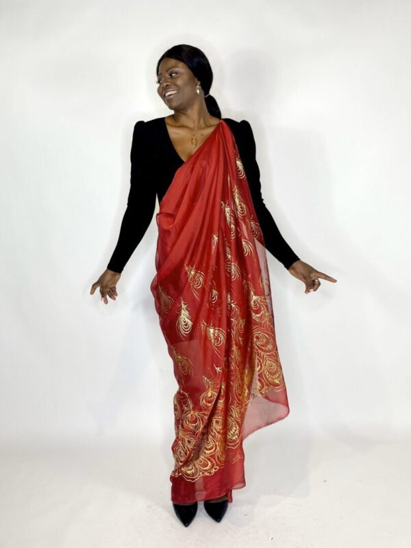 Woman wearing a red saree with gold designs.