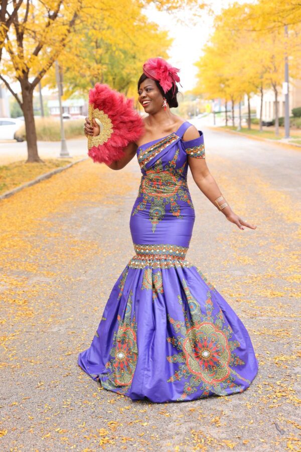 Woman in purple dress holding a fan.