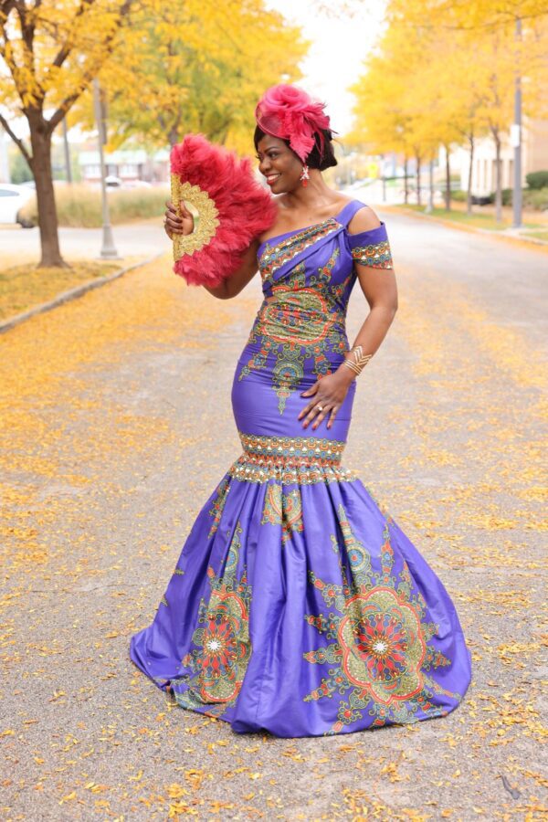 Woman in purple dress holding a fan.