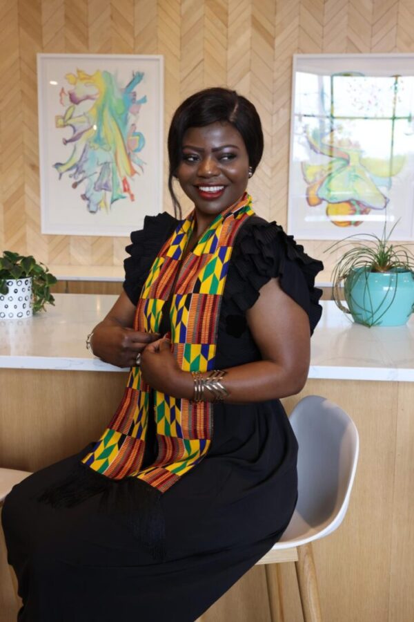 Woman in black dress with kente cloth.