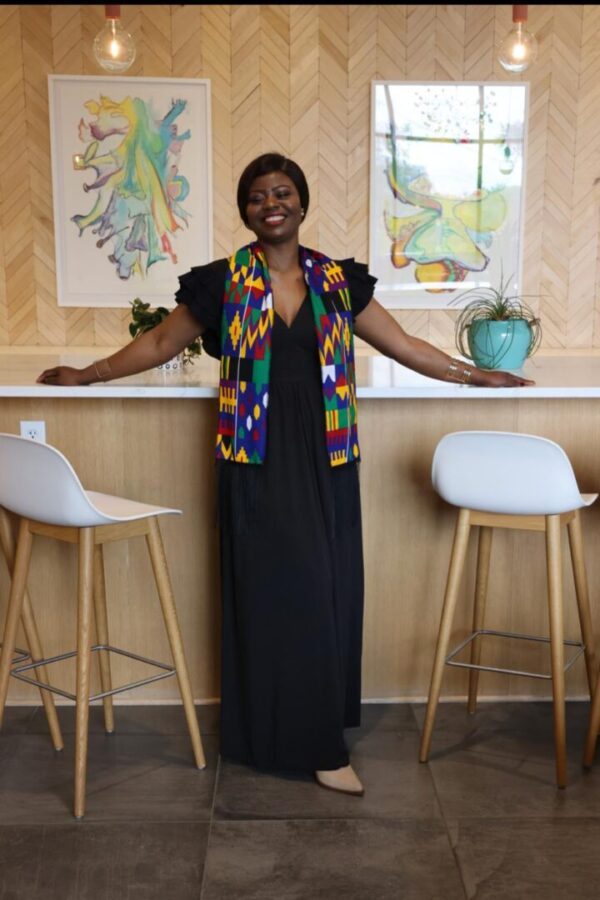 A woman standing in front of two white stools.