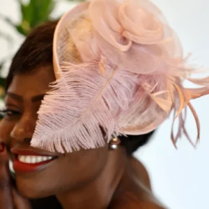 Woman with pink feathered hat smiling.
