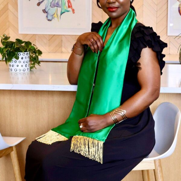 Woman wearing a green fringed scarf.