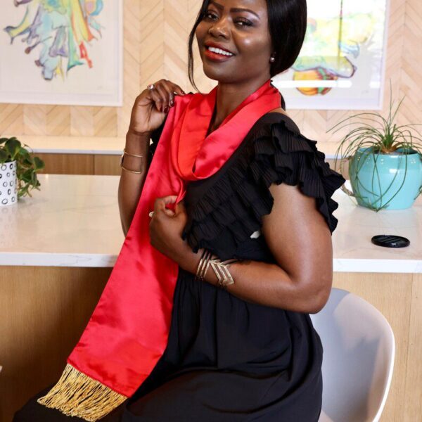 Woman in a black dress with a red sash.