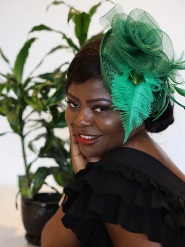 Woman with green feather hat smiling.