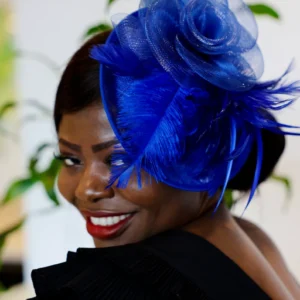 Woman with blue feathered hat smiling.