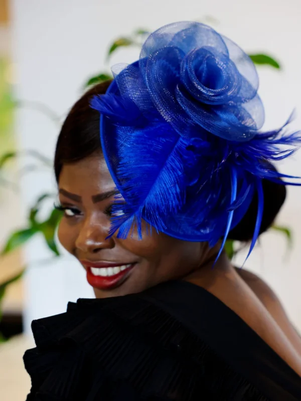 Woman with blue feathered hat smiling.