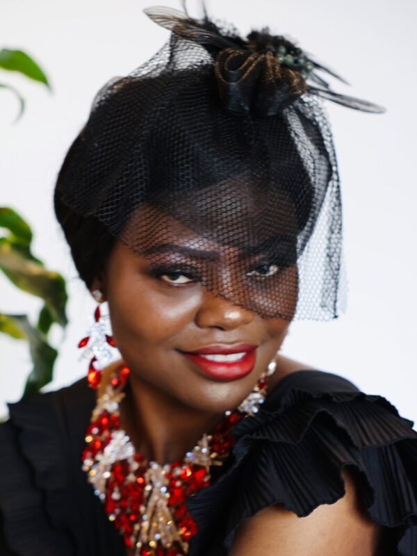 Woman wearing a black veil and red necklace.