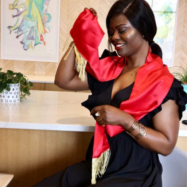 Woman in black dress with red sash.