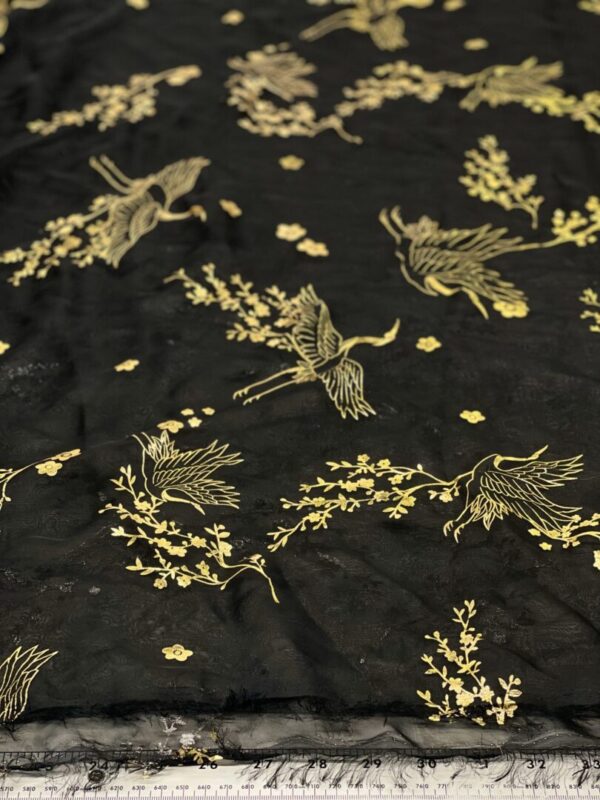 Black sheer fabric with gold cranes and flowers.