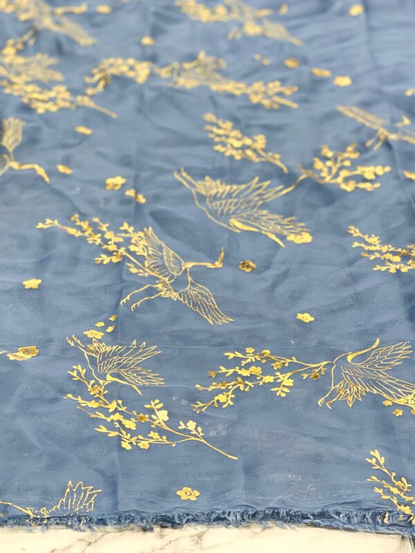 Blue fabric with gold cranes and flowers.