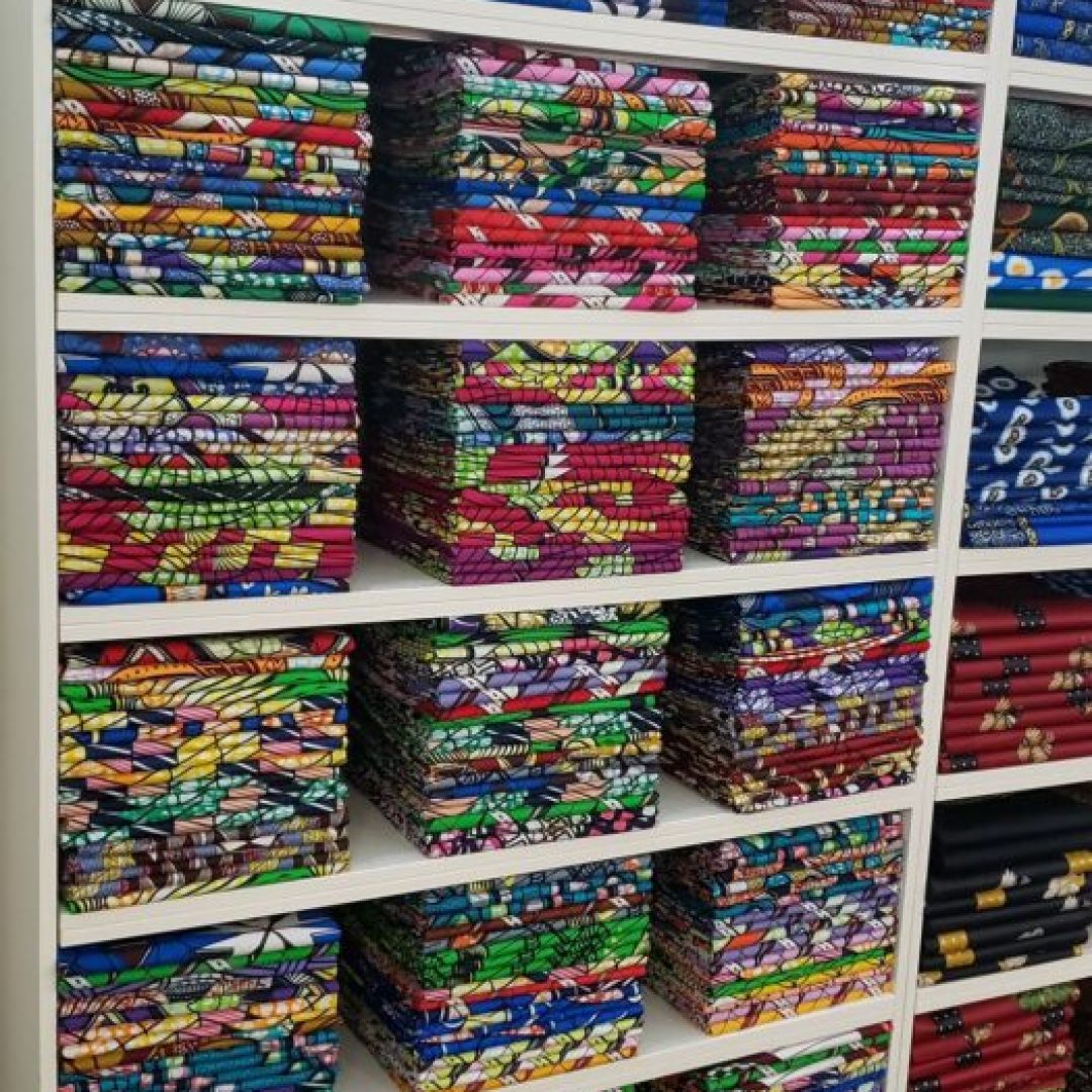Colorful patterned fabric stacks on shelves.